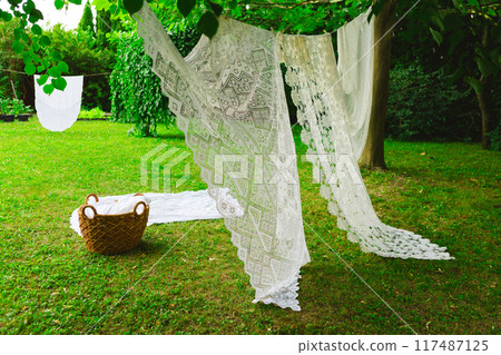 Washing day with laundry on clothesline, White clean sheets outdoors. 117487125