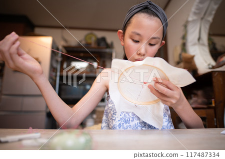 Girl doing embroidery Girl doing embroidery 117487334