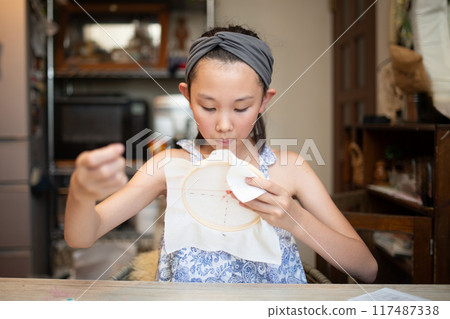 Girl doing embroidery Girl doing embroidery 117487338