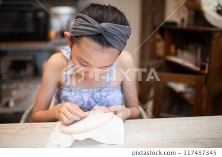Girl doing embroidery 117487345