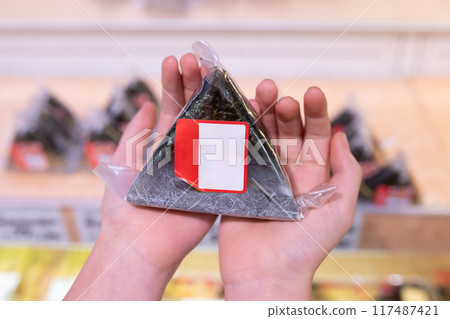 Child's hand holding a commercially available rice ball 117487421
