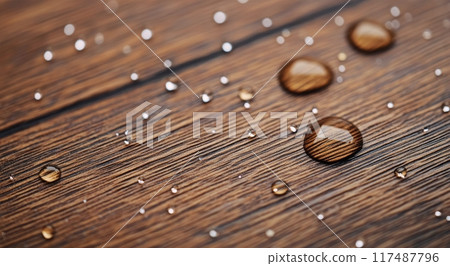 Water droplets resting on a wooden surface in soft natural light 117487796