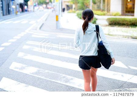 Back view of a young woman going to a sports gym Residential area City center Diet Personal gym Muscle training girl 117487879
