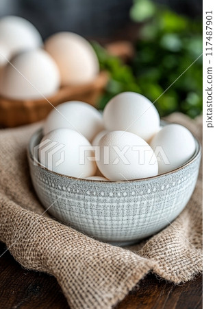 A rustic bowl filled with white and brown eggs on a textured burlap surface 117487901