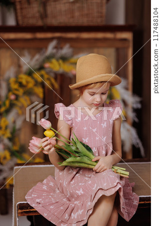A young girl wearing a pink dress and a straw hat is smiling A young girl wearing a pink dress and a straw hat is smiling 117488104