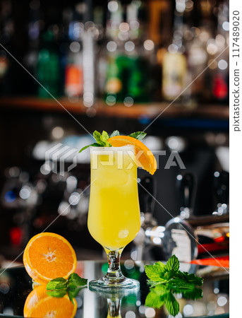 Refreshing yellow citrus cocktail with orange slice garnish and fresh mint, perfect for summer 117489020
