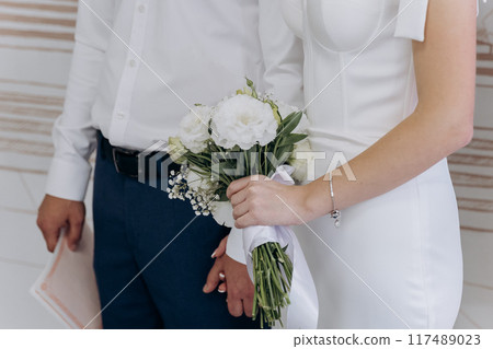 Elegant wedding moment with bride and groom holding hands and bouquet, symbolizing love and unity 117489023