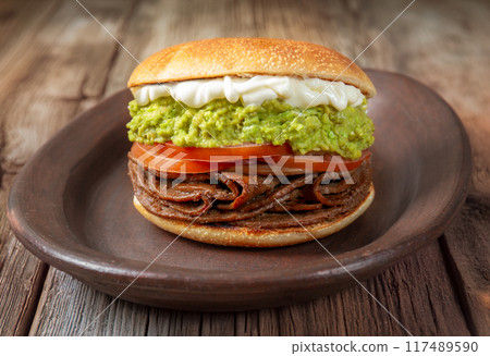 CHILEAN FOOD. Sandwich Churrasco italiano on colors of italian flag. Popular sandwich with round bread, beef, avocado guacamole, tomatoes and mayonnaise CHILEAN FOOD. Sandwich Churrasco italiano on colors of italian flag. Popular sandwich with round bread, beef, avocado guacamole, tomatoes and mayonnaise 117489590