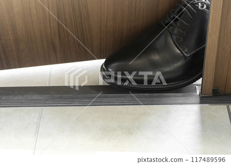 圖為一名銷售人員將商務鞋放在前門以防止門關閉。 圖為一名銷售人員將商務鞋放在前門以防止門關閉。 117489596