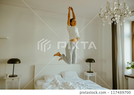Joyful Moments Jumping on the Bed in a Cozy and Comfortable Bedroom Filled with Cheer 117489700