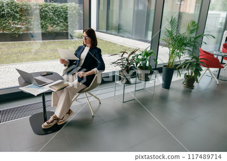 Modern Businesswoman Working in Contemporary Office with Plants and Natural Light Modern Businesswoman Working in Contemporary Office with Plants and Natural Light 117489714