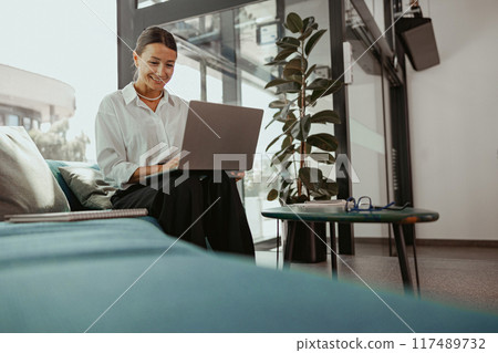 A Professional Woman is Actively Engaged in Working on Her Laptop in a Modern Office Space 117489732