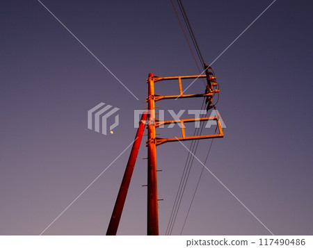 Telegraph pole and moon bathed in the setting sun Telegraph pole and moon bathed in the setting sun 117490486