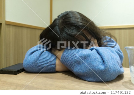 一個女人臉朝下趴在桌上睡覺 117491122