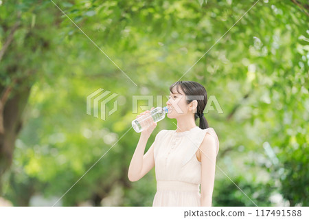 Profile of a woman drinking water from a plastic bottle 117491588