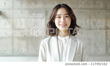 一個穿著西裝的女人站在混凝土牆前 117492162