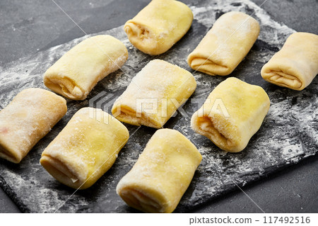 Freshly rolled stuffed crepes, ready for cooking, showcasing traditional homemade preparation 117492516