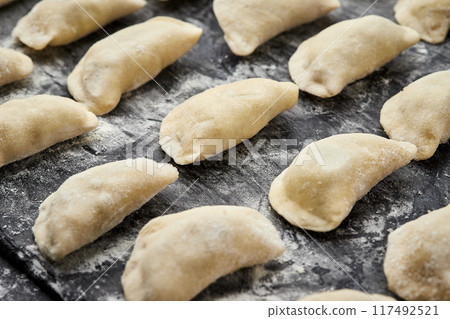 Freshly prepared homemade dumplings ready for cooking, showcasing traditional culinary skills Freshly prepared homemade dumplings ready for cooking, showcasing traditional culinary skills 117492521