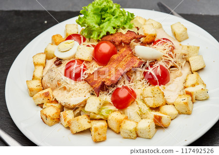 Fresh Caesar salad with cherry tomatoes, crispy bacon, and parmesan cheese, perfect for a light meal 117492526