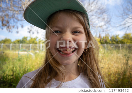 The little girl smiles. Permanent teeth appeared. 117493452