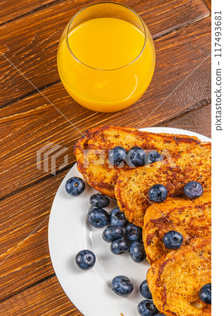 French toast on a white plate with blueberries and orange juice for breakfast French toast on a white plate with blueberries and orange juice for breakfast 117493681