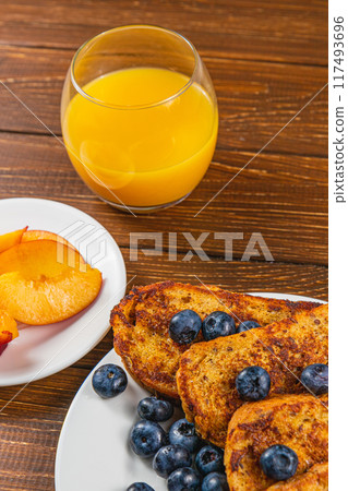 French toast on a plate with blueberries, orange juice, nectarine for breakfast 117493696
