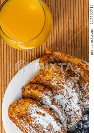 French toast on a white plate with blueberries and orange juice for breakfast French toast on a white plate with blueberries and orange juice for breakfast 117493712