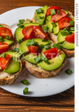 Avocado toast topped with tomato and green onion on a slice of carrot bread 117493714