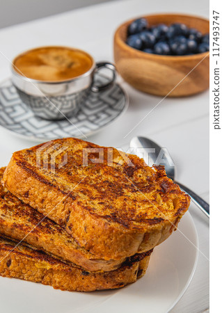 French toast on a white plate with blueberries and coffee for breakfast 117493747