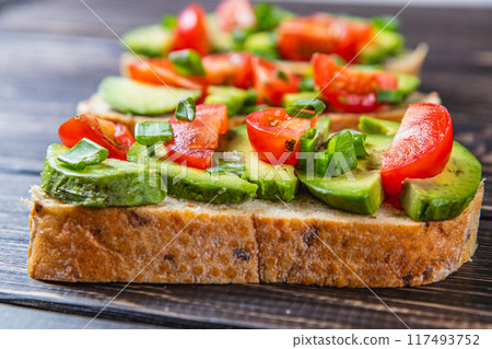 Avocado toast topped with tomato and green onion on a slice of carrot bread Avocado toast topped with tomato and green onion on a slice of carrot bread 117493752