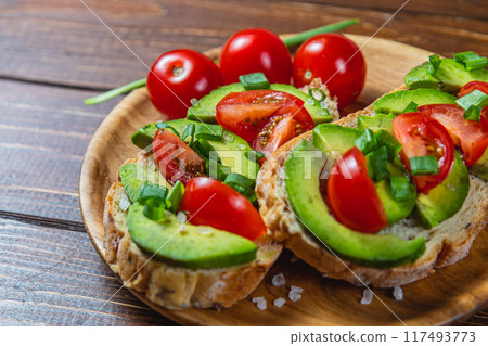 Avocado toast topped with tomato and green onion on a slice of carrot bread Avocado toast topped with tomato and green onion on a slice of carrot bread 117493773