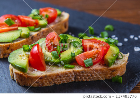 Avocado toast topped with tomato and green onion on a slice of carrot bread Avocado toast topped with tomato and green onion on a slice of carrot bread 117493776