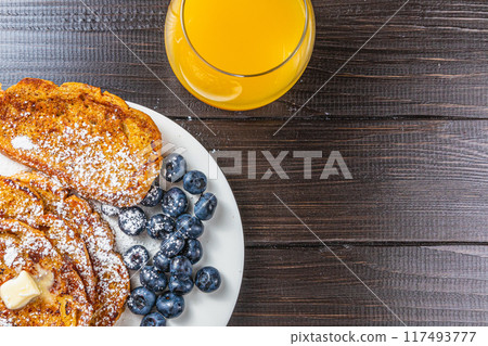French toast on a white plate with blueberries and orange juice for breakfast French toast on a white plate with blueberries and orange juice for breakfast 117493777