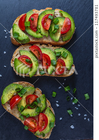 Avocado toast topped with tomato and green onion on a slice of carrot bread Avocado toast topped with tomato and green onion on a slice of carrot bread 117493781