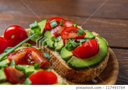 Avocado toast topped with tomato and green onion on a slice of carrot bread Avocado toast topped with tomato and green onion on a slice of carrot bread 117493784