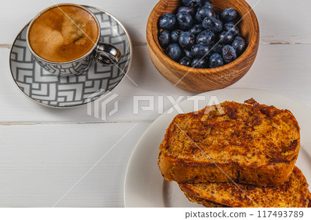 French toast on a white plate with blueberries and coffee for breakfast 117493789