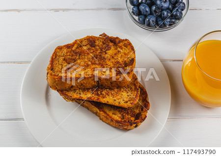 French toast on a white plate with blueberries and orange juice for breakfast 117493790