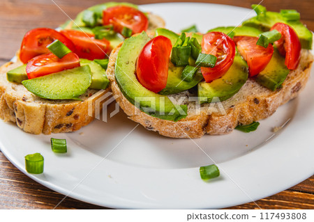 Avocado toast topped with tomato and green onion on a slice of carrot bread Avocado toast topped with tomato and green onion on a slice of carrot bread 117493808