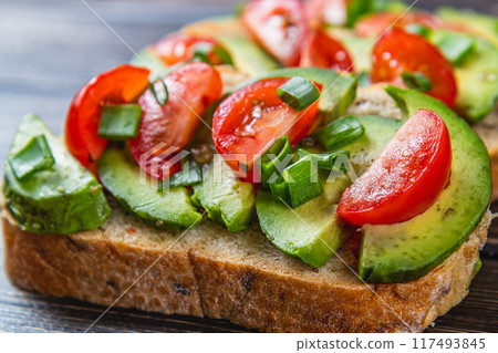 Avocado toast topped with tomato and green onion on a slice of carrot bread 117493845