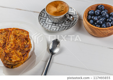 French toast on a white plate with blueberries and coffee for breakfast 117493855