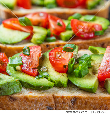Avocado toast topped with tomato and green onion on a slice of carrot bread Avocado toast topped with tomato and green onion on a slice of carrot bread 117493860