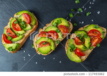 Avocado toast topped with tomato and green onion on a slice of carrot bread 117493862