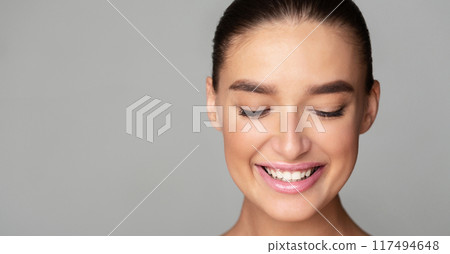 A young woman is smiling with her eyes closed in a joyful expression. Her face is illuminated by happiness as she enjoys a moment of bliss, copy space 117494648