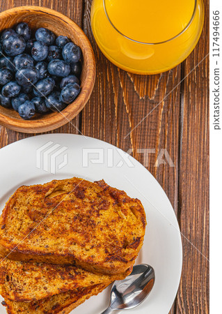 French toast on a white plate with blueberries and orange juice for breakfast French toast on a white plate with blueberries and orange juice for breakfast 117494666