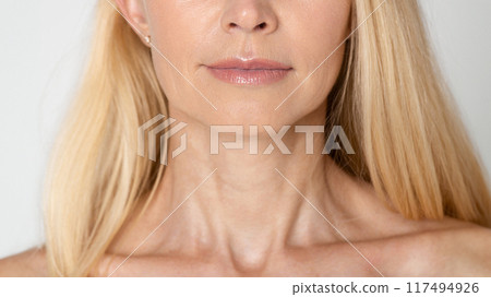 A close-up portrait of a womans neck and shoulders. She has long, blonde hair that falls straight down her back. Her skin is smooth and clear, cropped A close-up portrait of a womans neck and shoulders. She has long, blonde hair that falls straight down her back. Her skin is smooth and clear, cropped 117494926