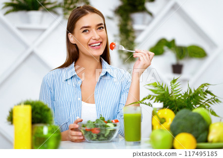 Happy Woman Eating Healthy Salad With Green Fresh Ingredients, Sitting At Kitchen 117495185