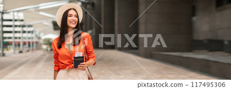Happy Tourist Lady In Hat Holding Passport And Boarding Pass Walking With Luggage At Modern Airport Outdoors, Looking Away, Copy Space. Passenger With Suitcase Arriving At Terminal Happy Tourist Lady In Hat Holding Passport And Boarding Pass Walking With Luggage At Modern Airport Outdoors, Looking Away, Copy Space. Passenger With Suitcase Arriving At Terminal 117495306