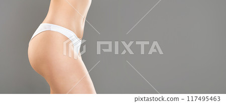 A young woman stands confidently in minimalist, white underwear against a clean, grey backdrop. Her posture highlights her natural curves and toned midsection, panorama with copy space A young woman stands confidently in minimalist, white underwear against a clean, grey backdrop. Her posture highlights her natural curves and toned midsection, panorama with copy space 117495463