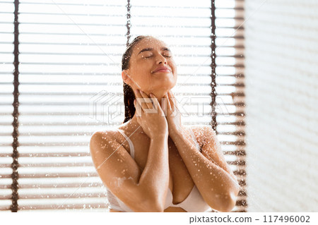 Woman washing body and hair under shower, standing with closed eyes, free space 117496002