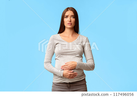 Pregnancy Stomachache. Sad Pregnant Woman Touching Belly Suffering From Pain Standing On Gray Background. Studio Shot 117496056